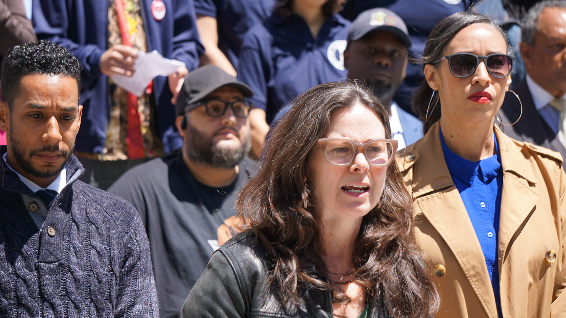 Christie Peale speaks at a City Hall rally against deed theft, with Brooklyn Borough President Antonio Reynoso to her left and Council Member Sandy Nurse to her right.